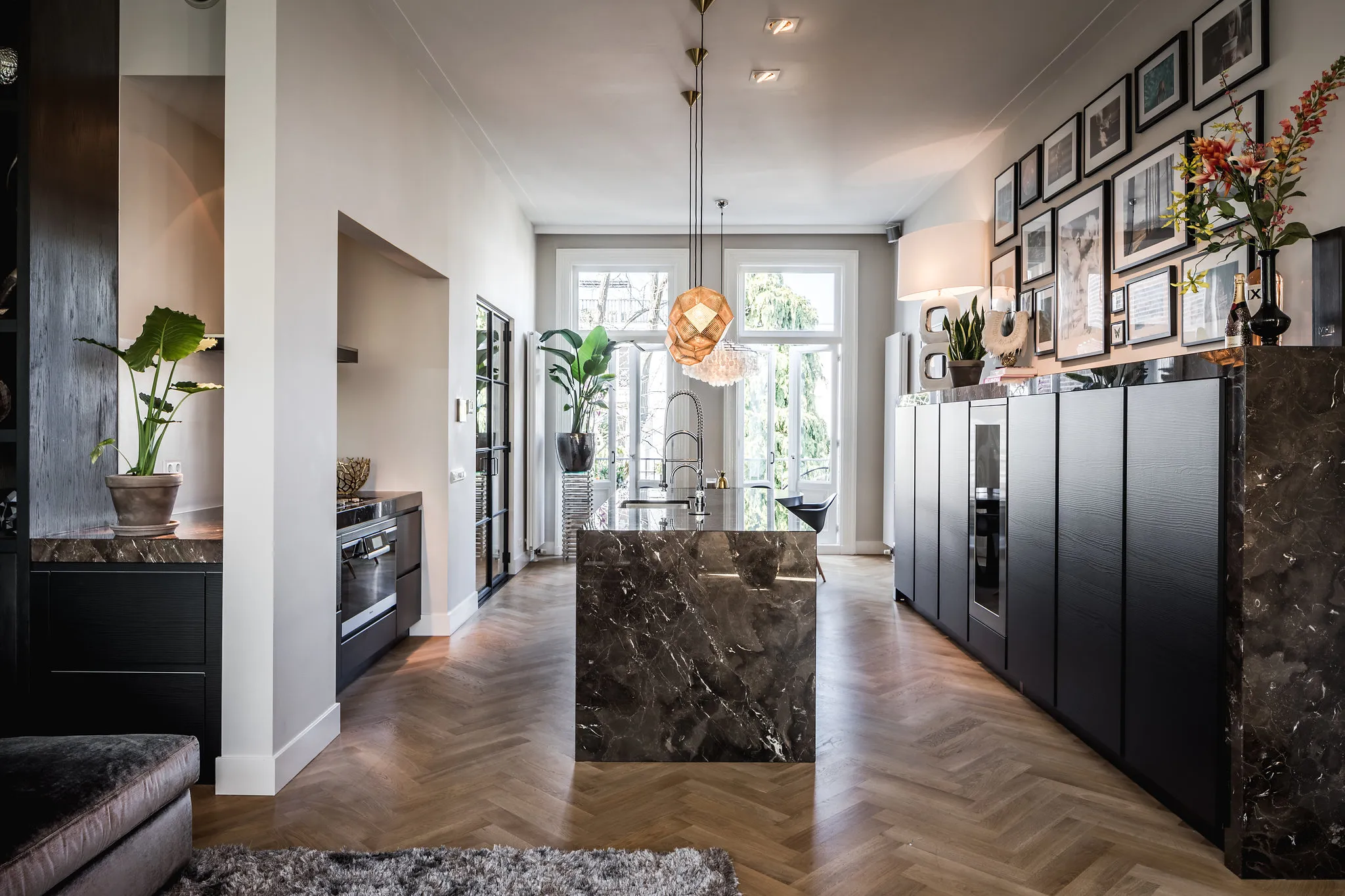 Keuken met eiland van Mistic Brown natuursteen, zwarte kastenwand en visgraatparket