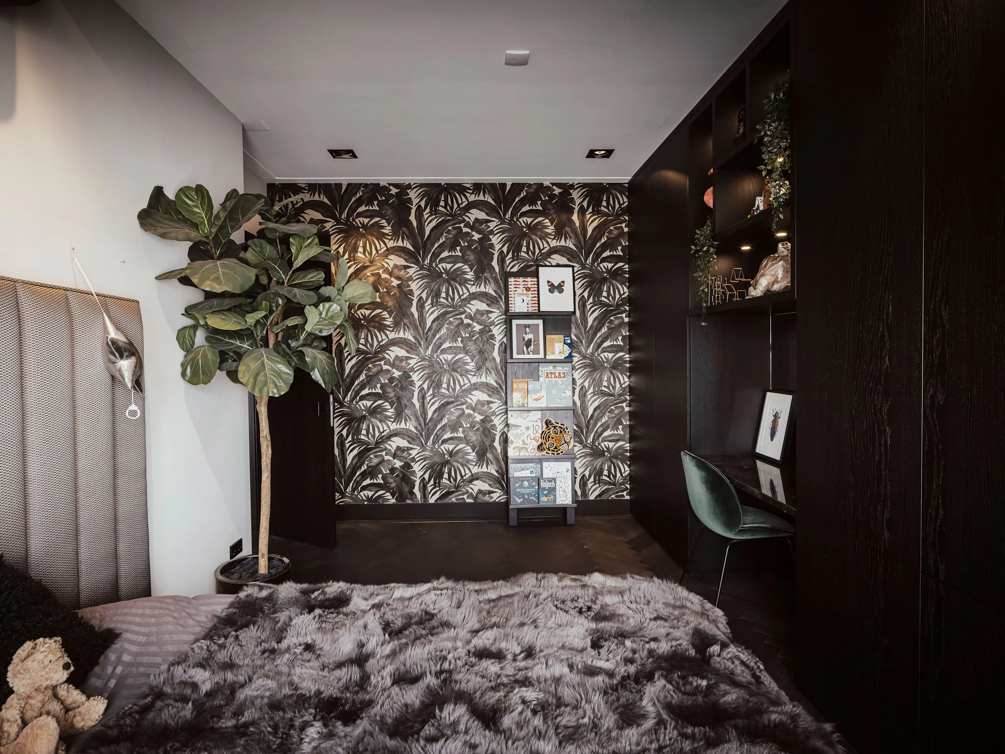 Kinderkamer met palmbladbehang en de donkere kastenwand met bureau en open vakken