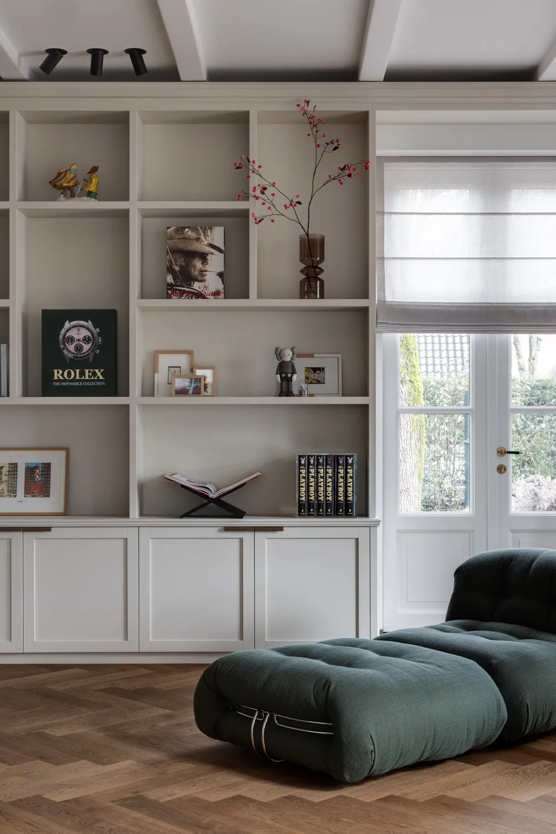 Open vakken met boeken en objecten boven dichte deuren met smalle bronzen grepen