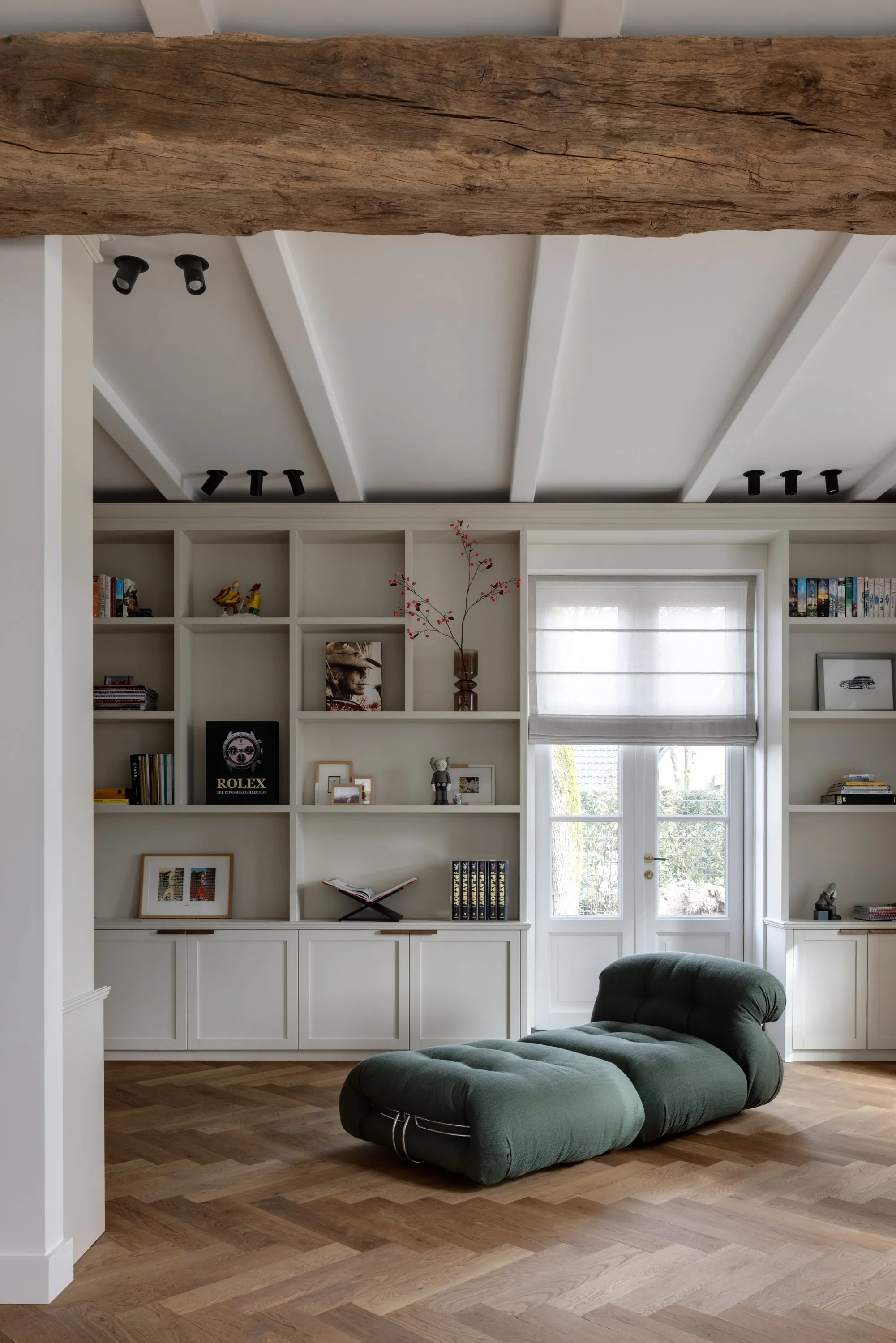 Kastenwand met open vakken en dichte deuren rond de tuindeuren, onder een oude eikenhouten balk