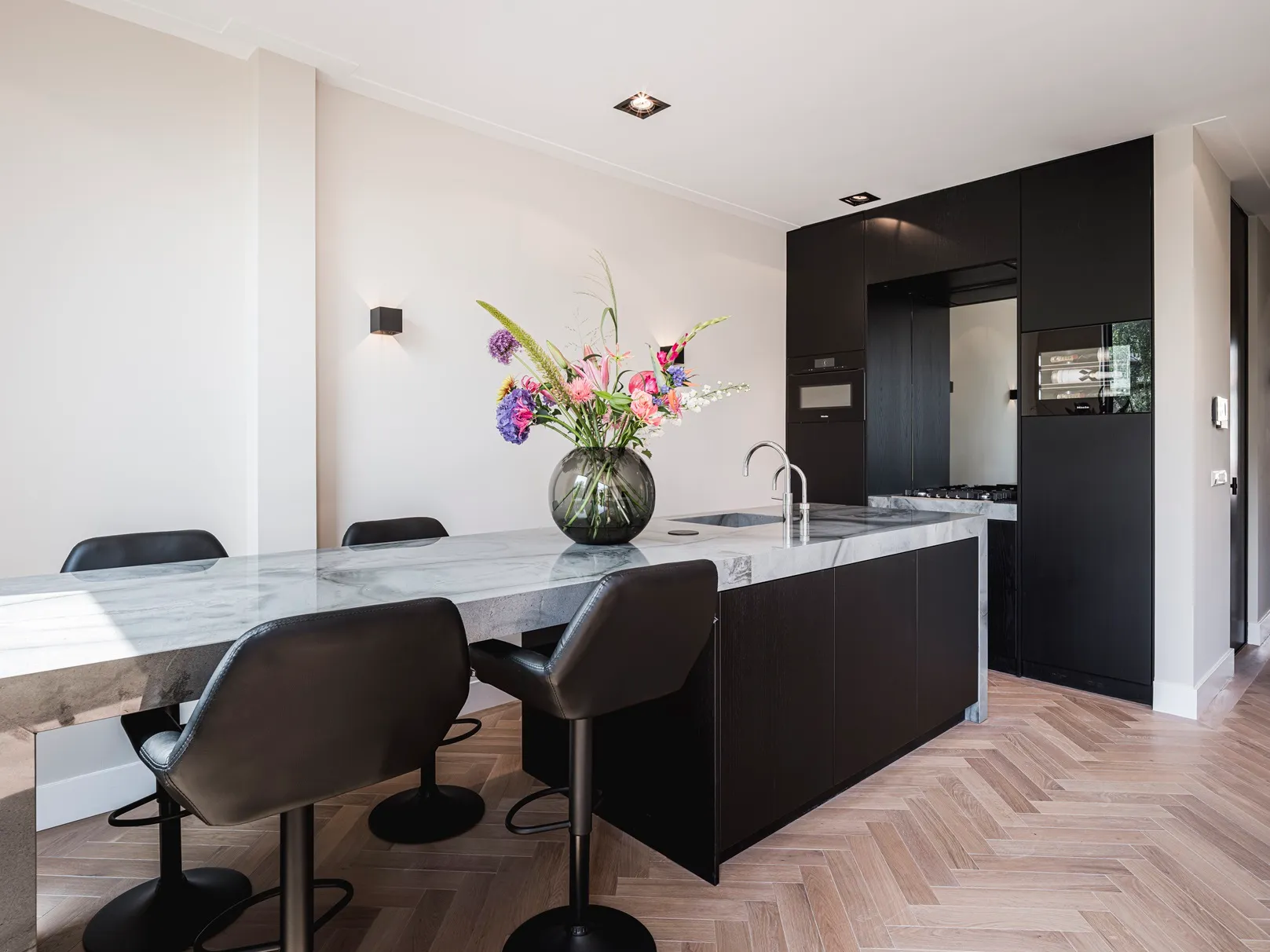 Keukeneiland met blad van Turtle Illusion graniet, matzwarte eiken fronten en kastenwand met Miele apparatuur