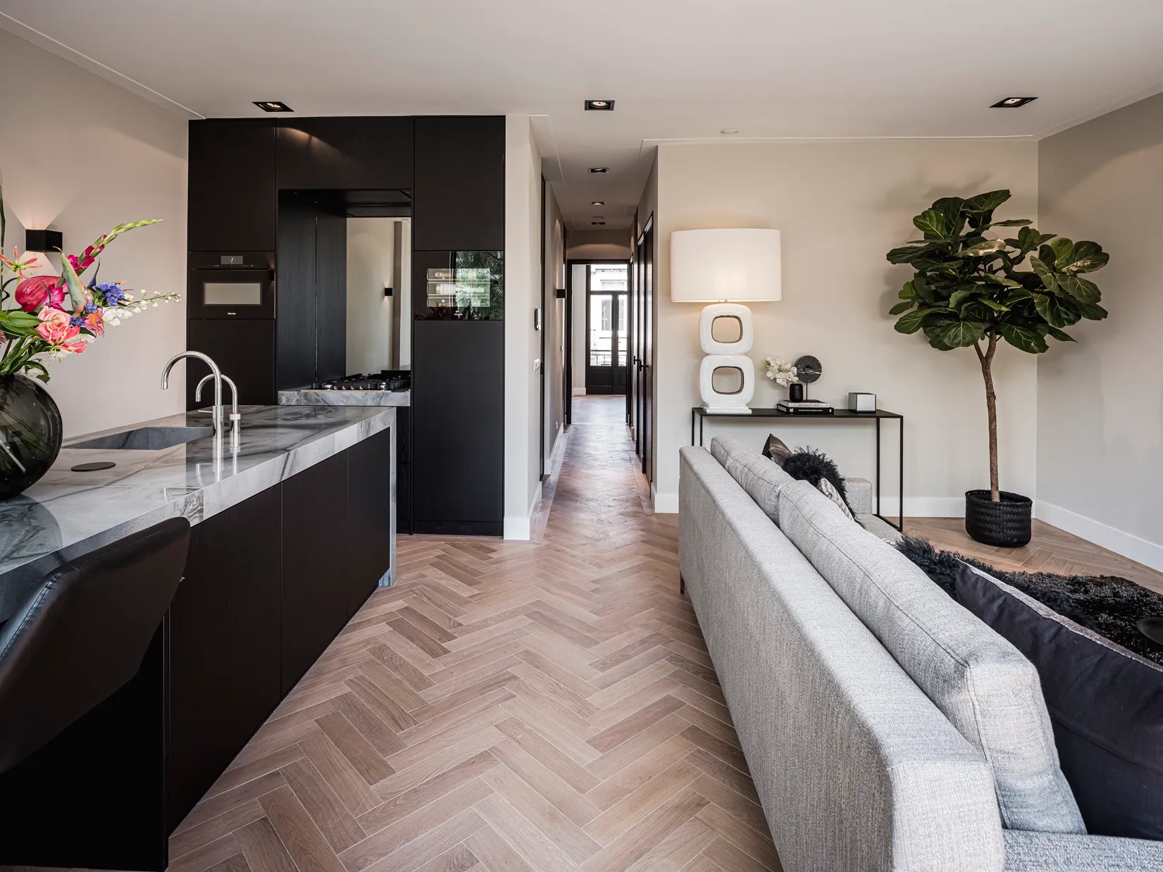Zicht langs het granieten werkblad naar de zithoek van het appartement