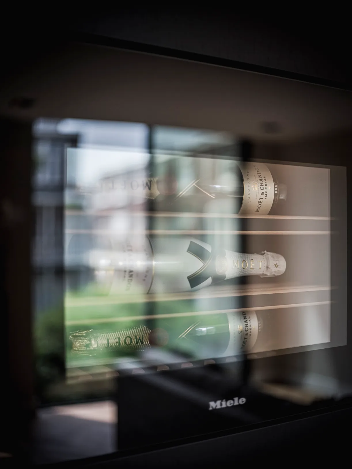 Champagneflessen achter de glazen deur van de Miele wijnklimaatkast in de matzwarte kastenwand