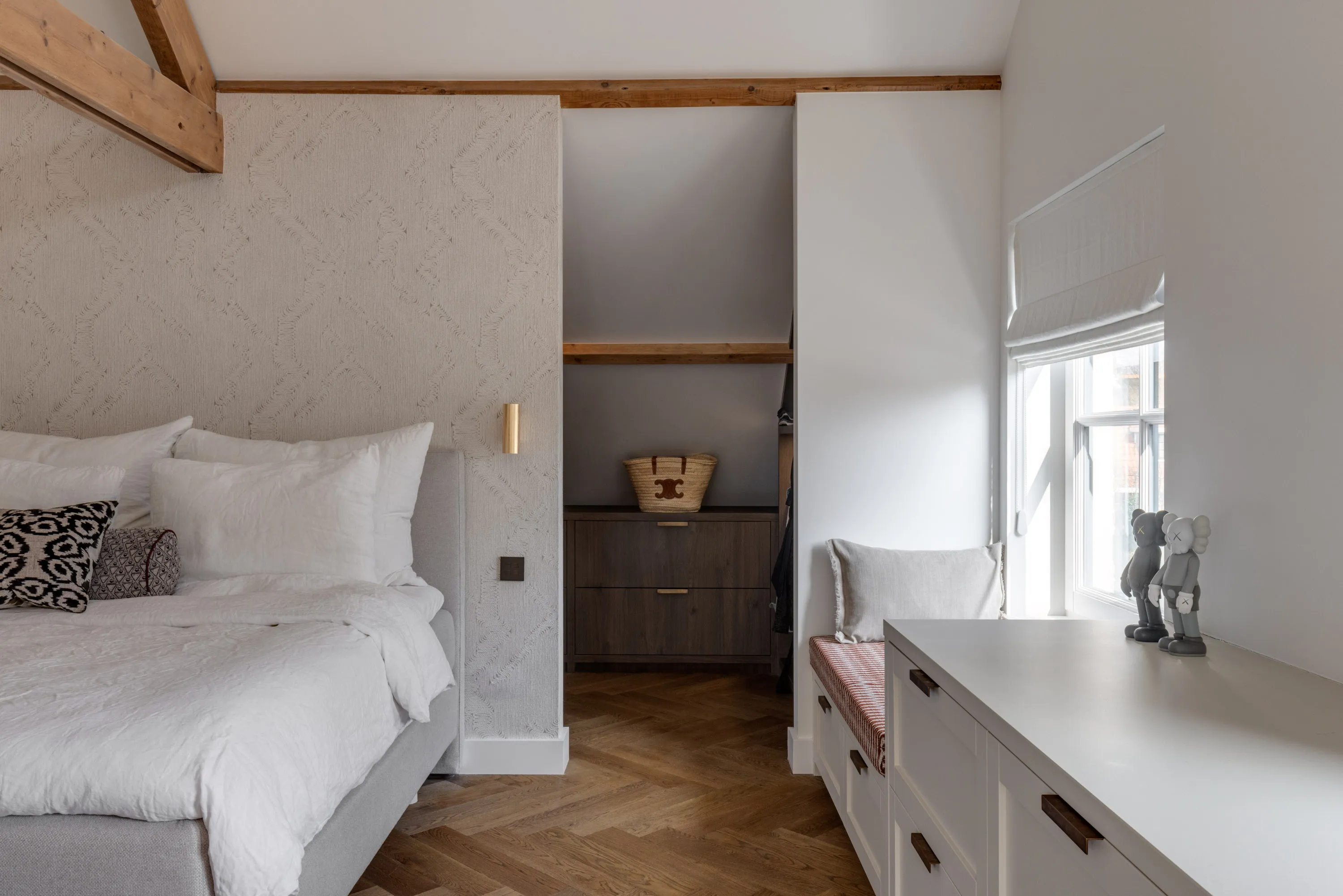 Doorkijk vanuit de master bedroom naar de inloopkast met donkere ladekast met messing grepen