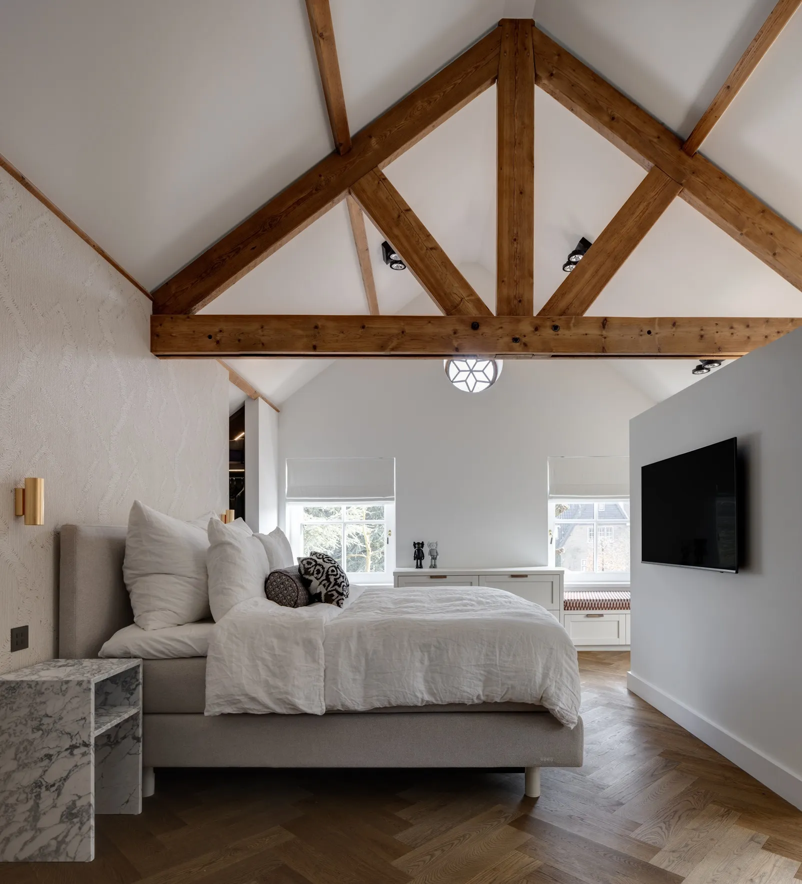 Master bedroom met houten spanten, maatwerk kast met zitbank onder het raam en toegang tot de inloopkast