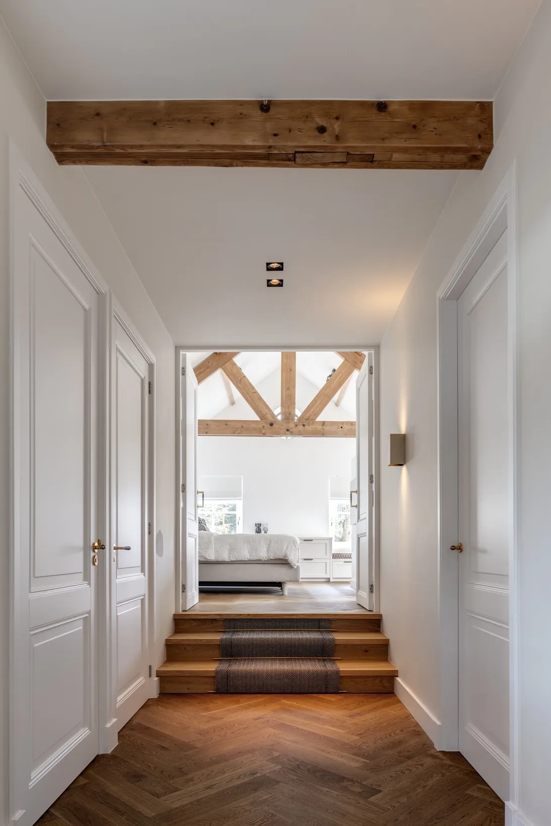 Overloop met traptreden naar de master bedroom, met zicht op de houten spanten en het maatwerk