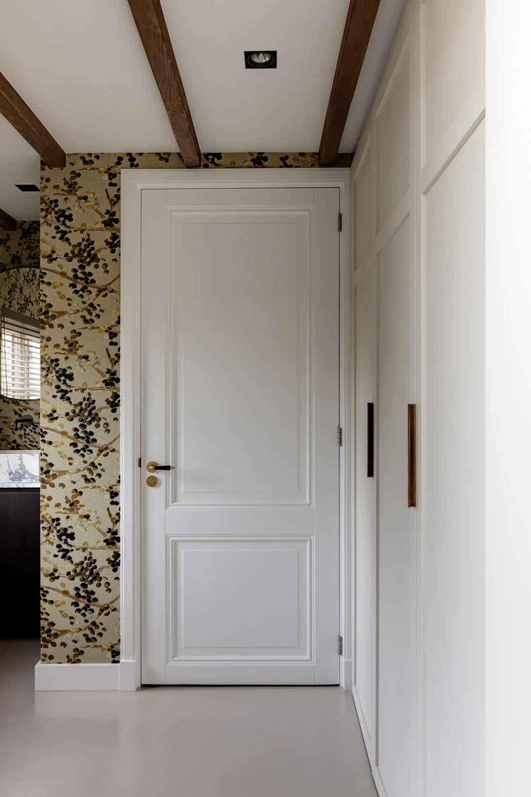 Doorkijk naar het toilet met botanisch behang, gezien vanuit de hal met witte kastenwand