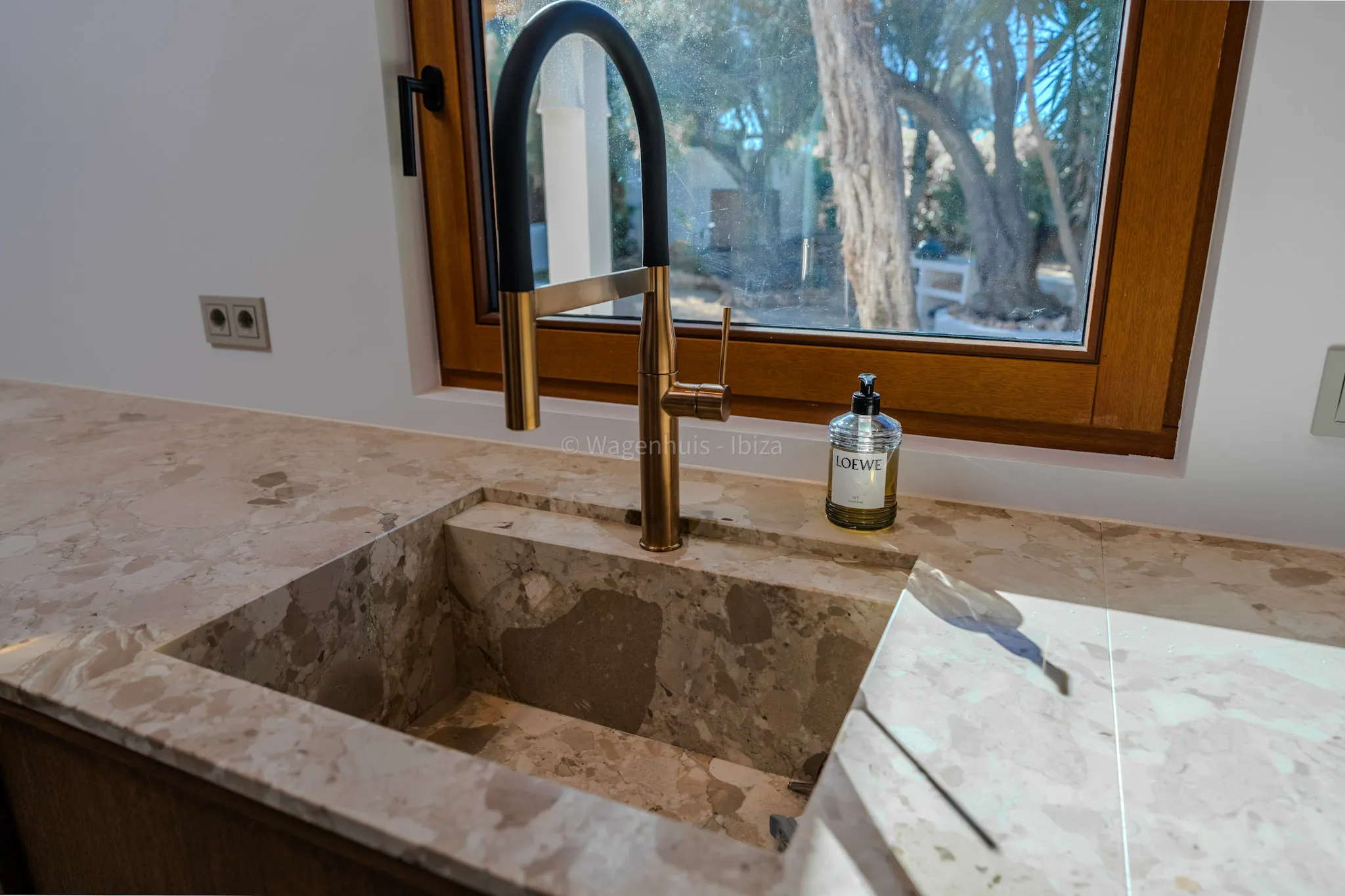 Spoelbak uit Ceppo Romano natuursteen met kraan in zwart en messing voor het keukenraam